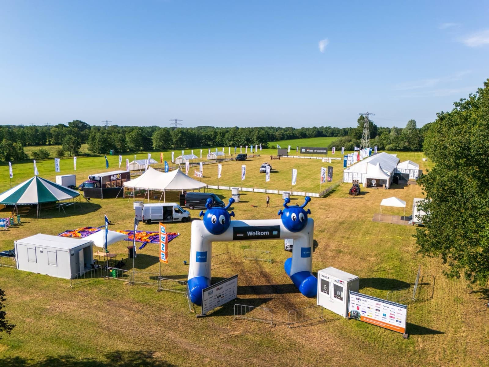 Dronefoto van de entree van een evenement met dranghekken en sponsorborden