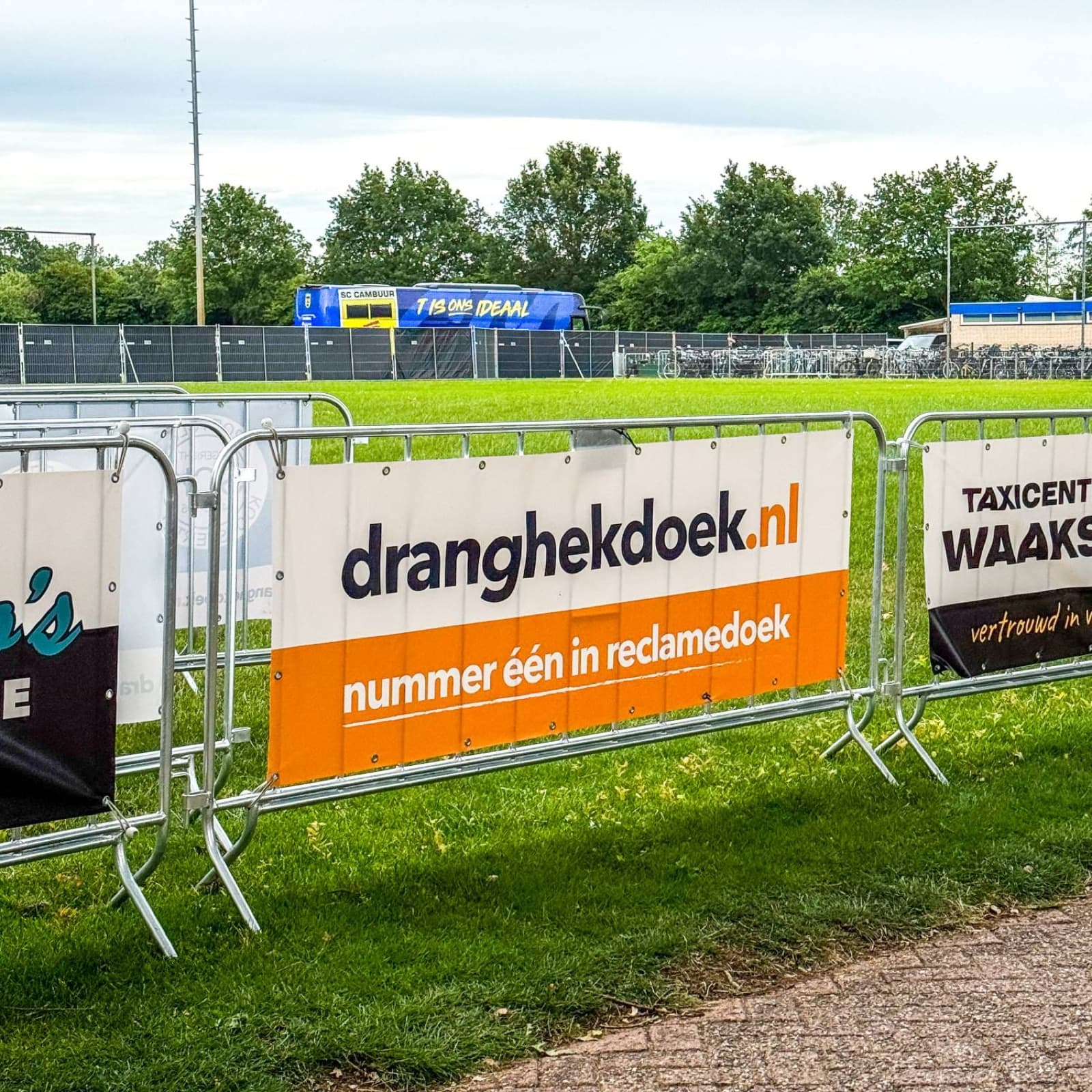 Dranghekdoeken van sponsors langs het veld, met de spelersbus van SC Cambuur op de achtergrond