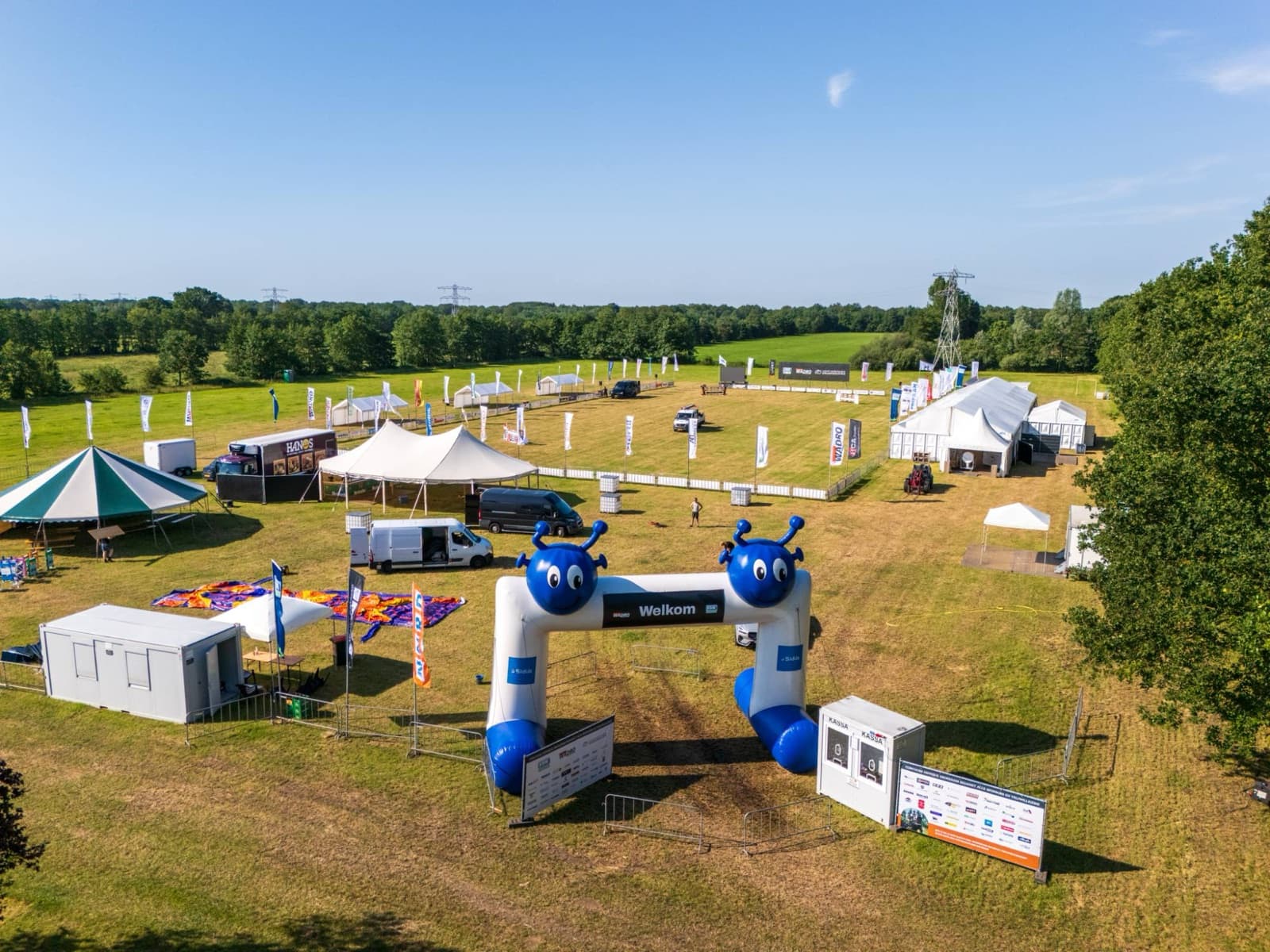 Luchtfoto van de entree van Concours Hippique Drogeham met sponsorborden en vlaggen rond het terrein