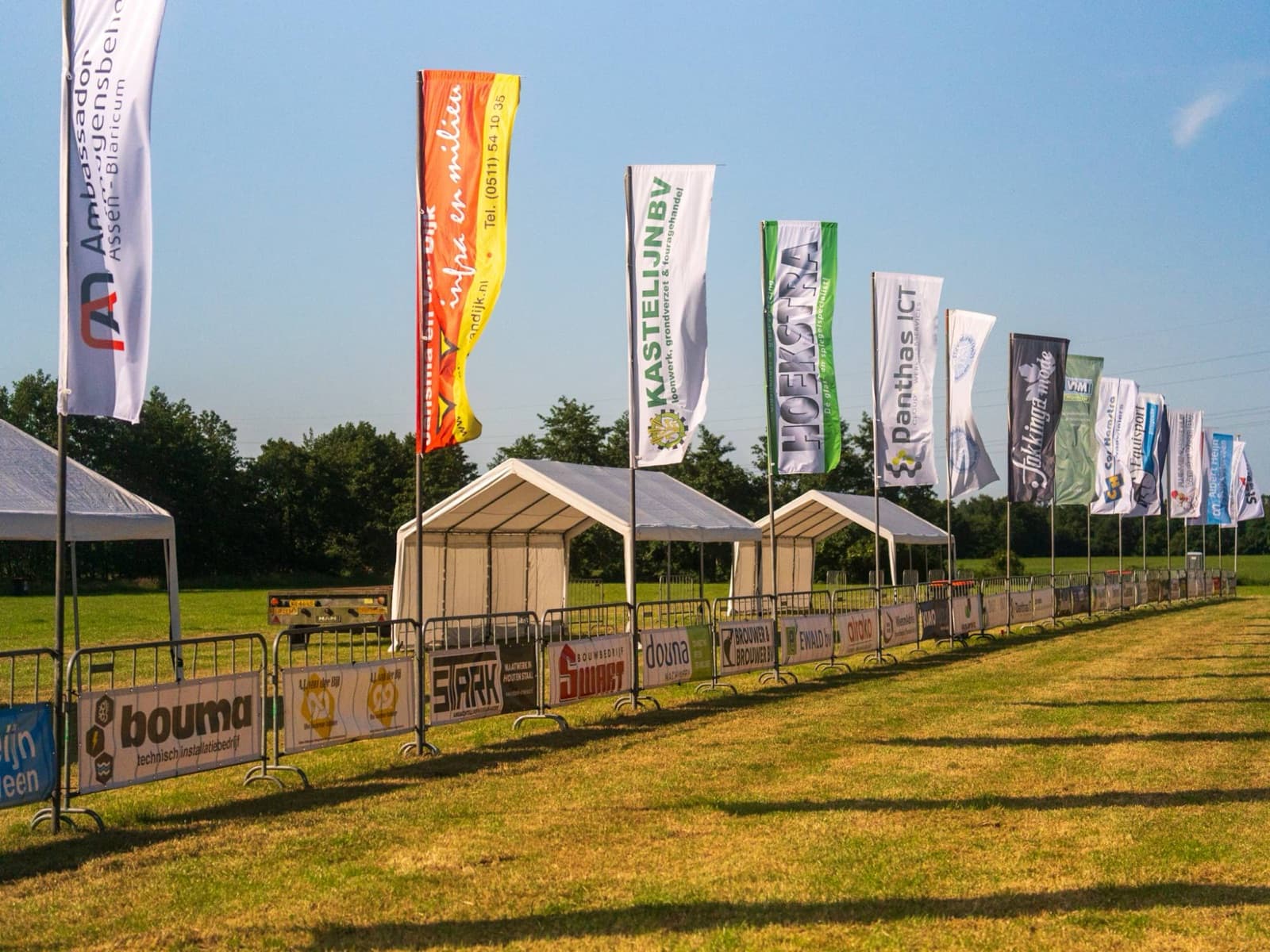 Een lange rij bedrukte baniervlaggen van sponsors langs een evenemententerrein