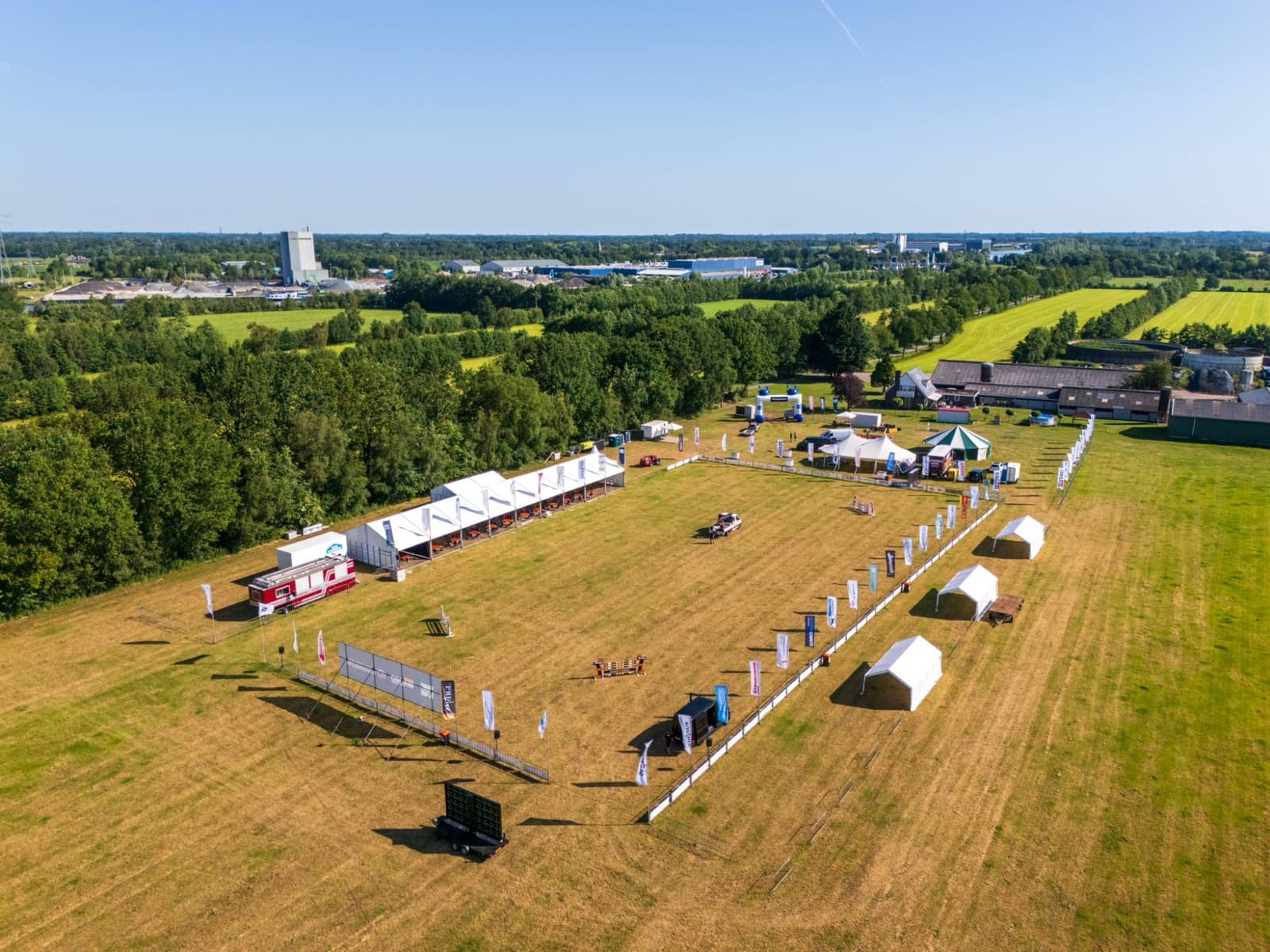 Dronefoto van een evenemententerrein afgezet met baniervlaggen en dranghekken