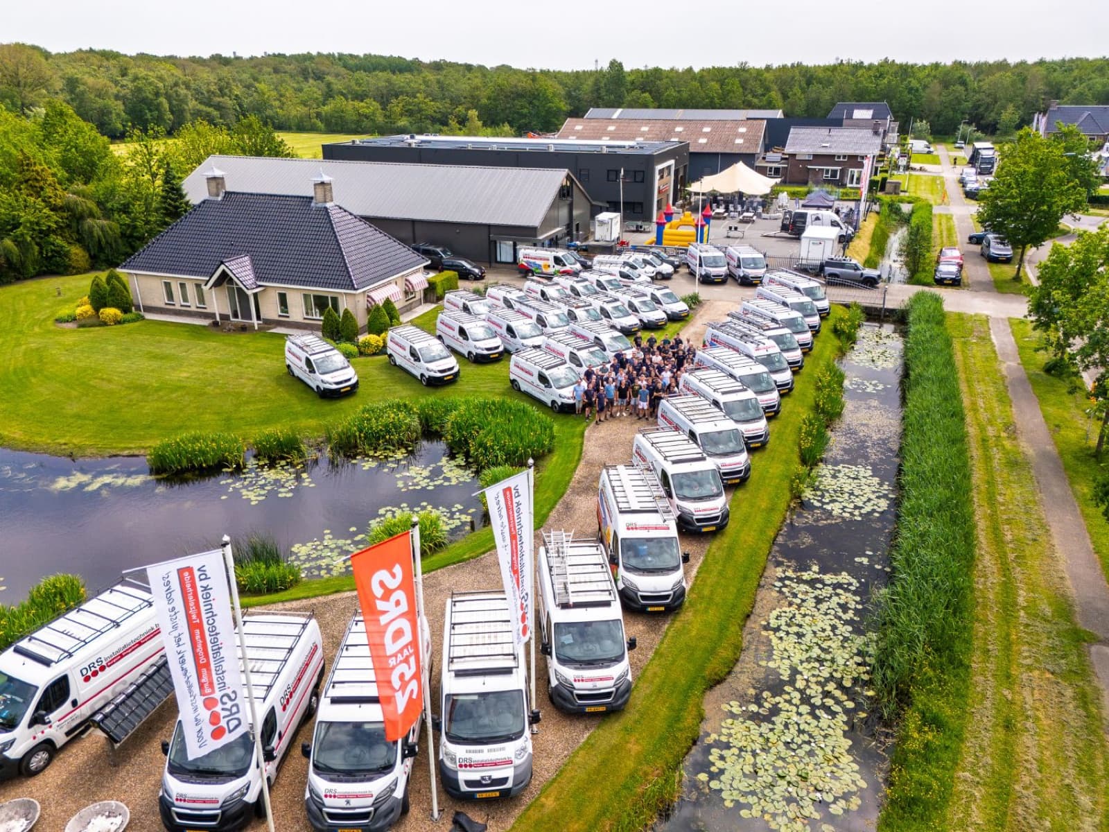 Dronefoto van het DRS-jubileum met baniervlaggen en de hele wagenvloot