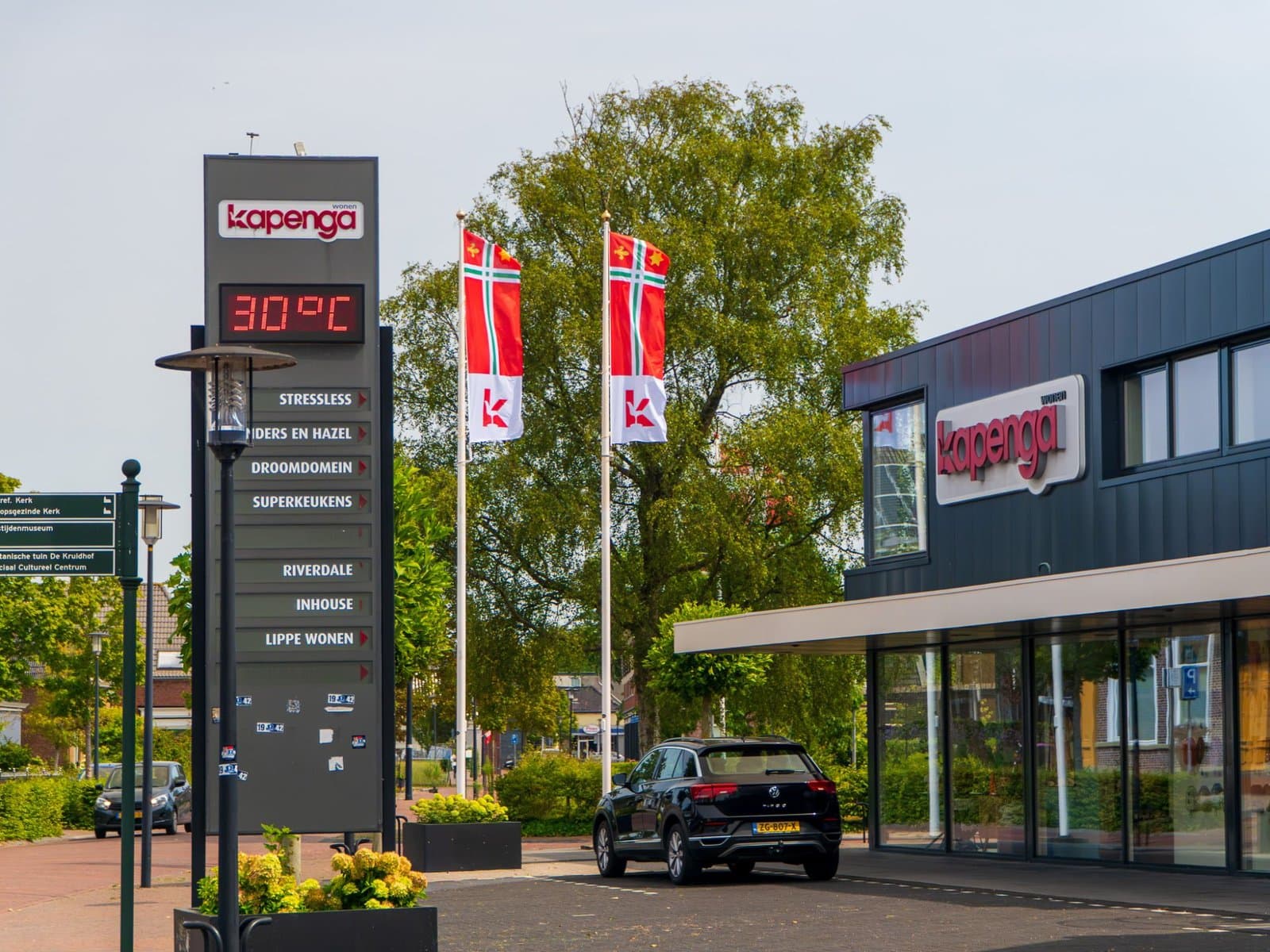 Twee baniervlaggen van Kapenga Wonen in de stijl van de Dorpsvlag Buitenpost bij de winkel