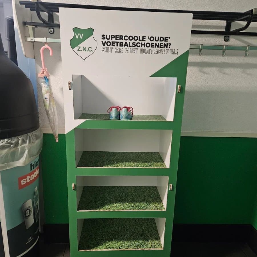 Weggeefkast van VV ZNC in clubkleuren, met planken van kunstgras en de tekst Zet ze niet buitenspel!